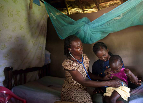 In a rural village outside of Kisumu, Kenya, a healthcare worker examines a child for possible symptoms of malaria.